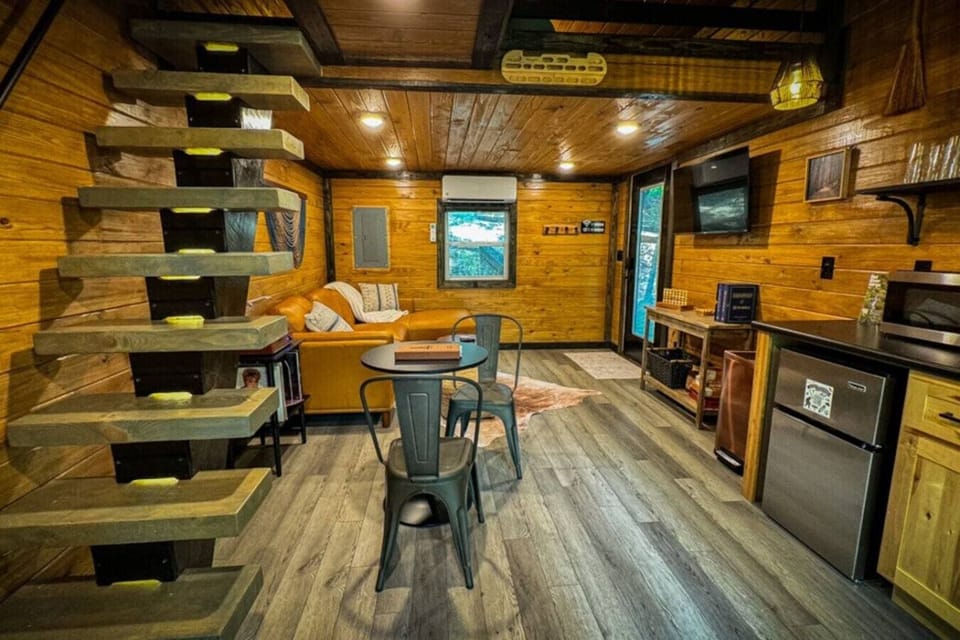 Cozy cabin living with a kitchenette, dining nook, and loft sleeping area above