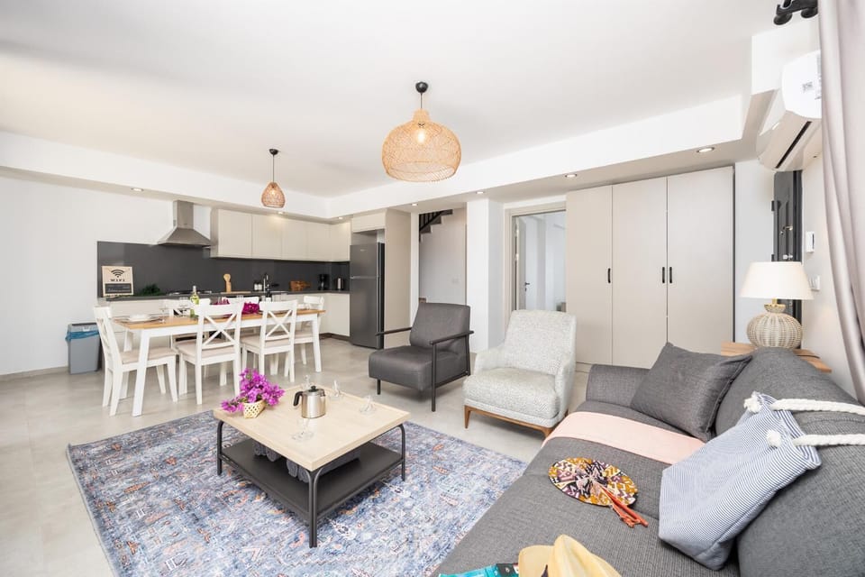Open-plan living room with sofa, dining area, kitchen, A/C, WiFi internet, and satellite TV