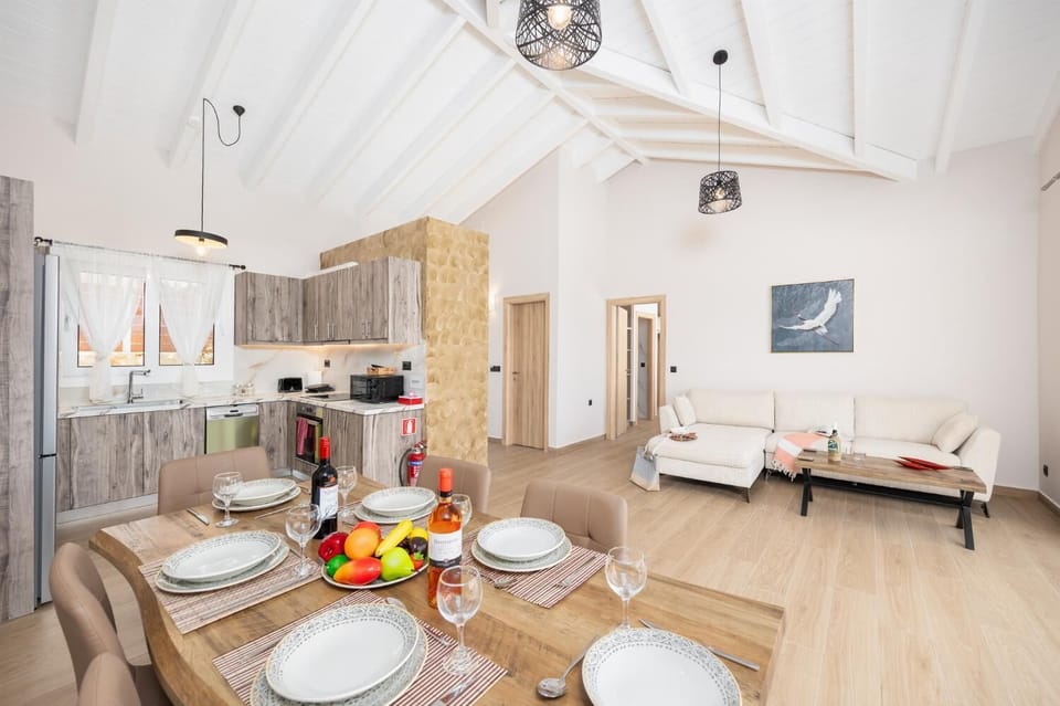 Open-plan living room with sofa, dining area, kitchen, A/C, WiFi internet, and satellite TV