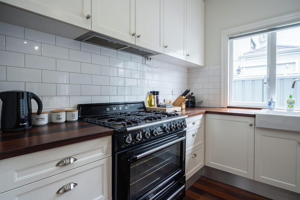 Cook with ease in a charming kitchen featuring white cabinetry, a large window, and a sleek black oven, creating a warm and inviting culinary space.