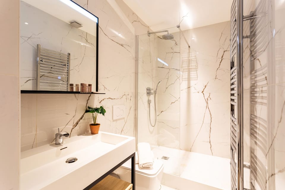 Bright, modern bathroom with a sink, mirror, toilet, and heated towel rack for your ultimate comfort.