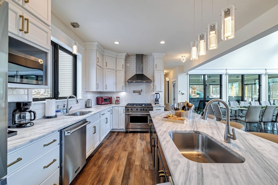 Chef’s kitchen with large island, stainless appliances, and bright lighting