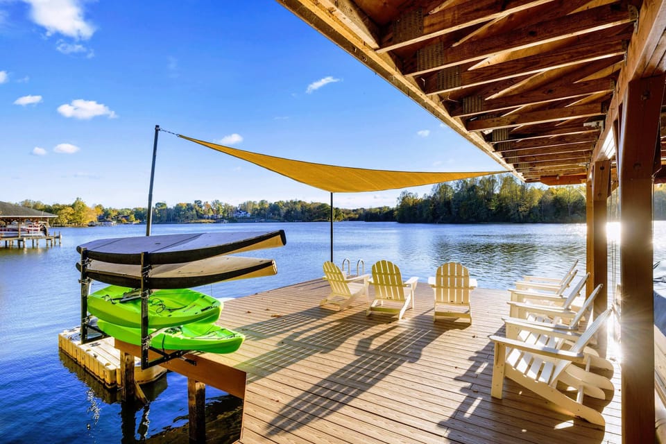 Dock - Yellow shade sail, Adirondack chairs, and kayaks line the spacious dock beside the covered boathouse.
