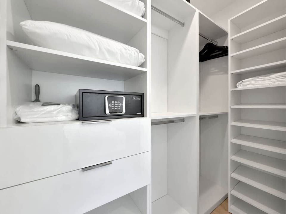 Stay organized and secure. This modern walk-in closet features a combination of open shelving, hanging space, and a high-gloss white drawer unit, plus a personal digital safe for valuables.