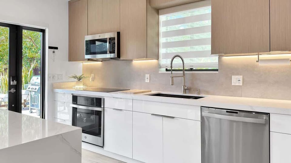Whip up your next culinary masterpiece. This sleek modern kitchen features a waterfall quartz counter, stainless steel appliances, and abundant cabinet space.