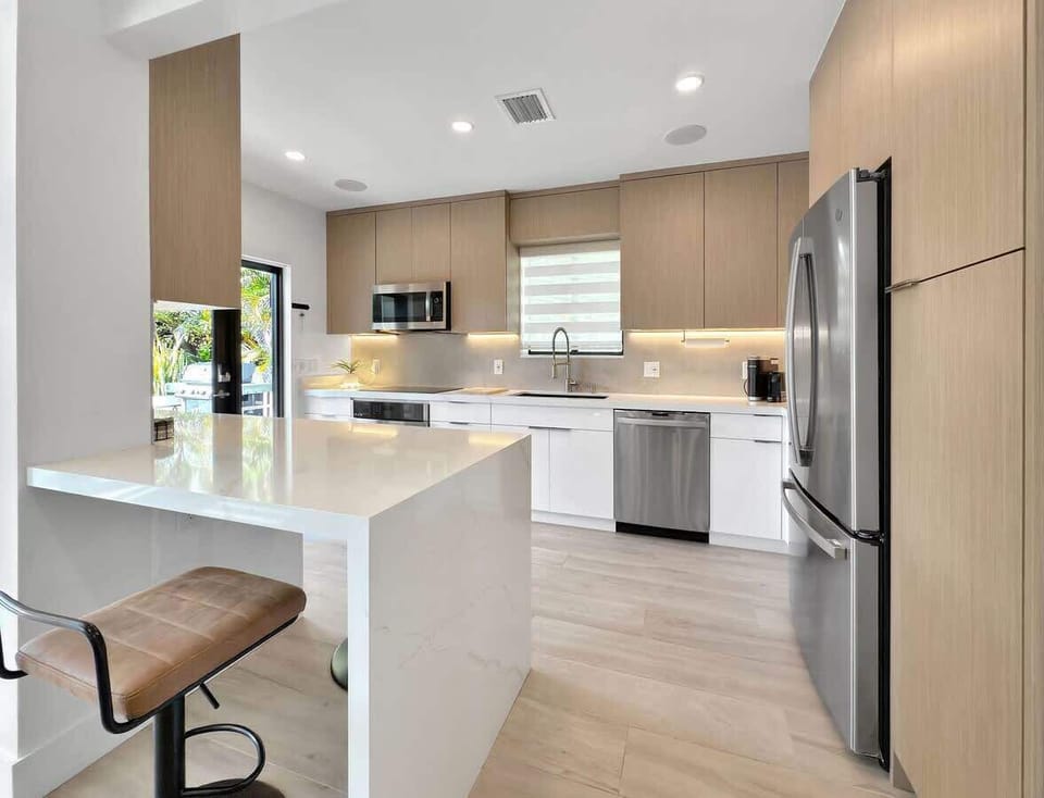 Whip up your next culinary masterpiece. This sleek modern kitchen features a waterfall quartz counter, stainless steel appliances, and abundant cabinet space.