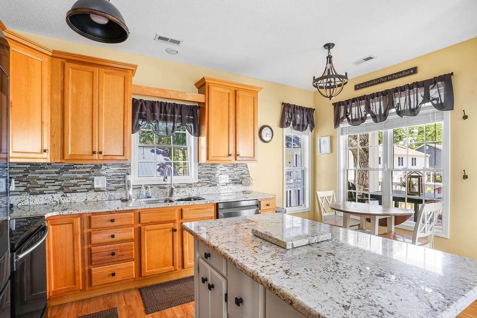 Sunlit kitchen with granite island and cozy breakfast nook