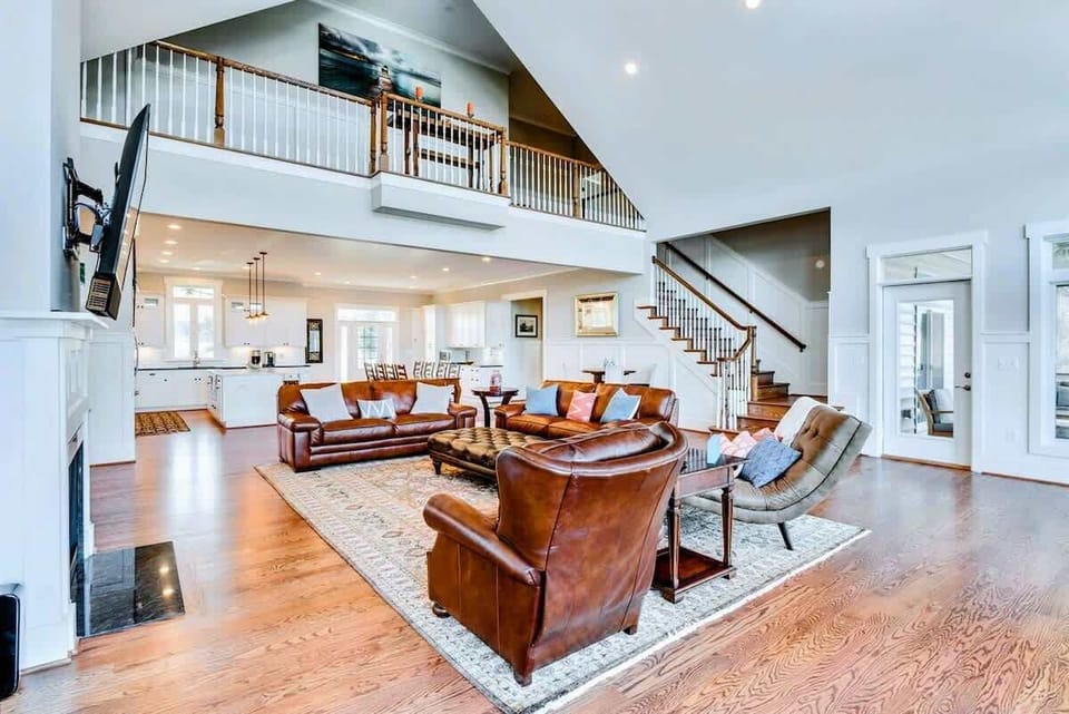 Expansive living space with high ceilings, leather seating, and open flow to the kitchen and dining area, perfect for group gatherings