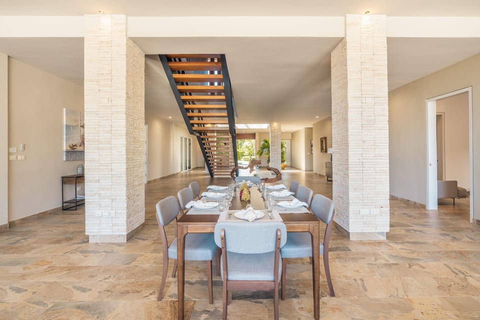 - Elegant dining area set beneath a statement staircase creating a stylish gathering space  
- Wide open layout supports shared meals and group celebrations  
- Natural tones and warm lighting enhance the home’s inviting atmosphere