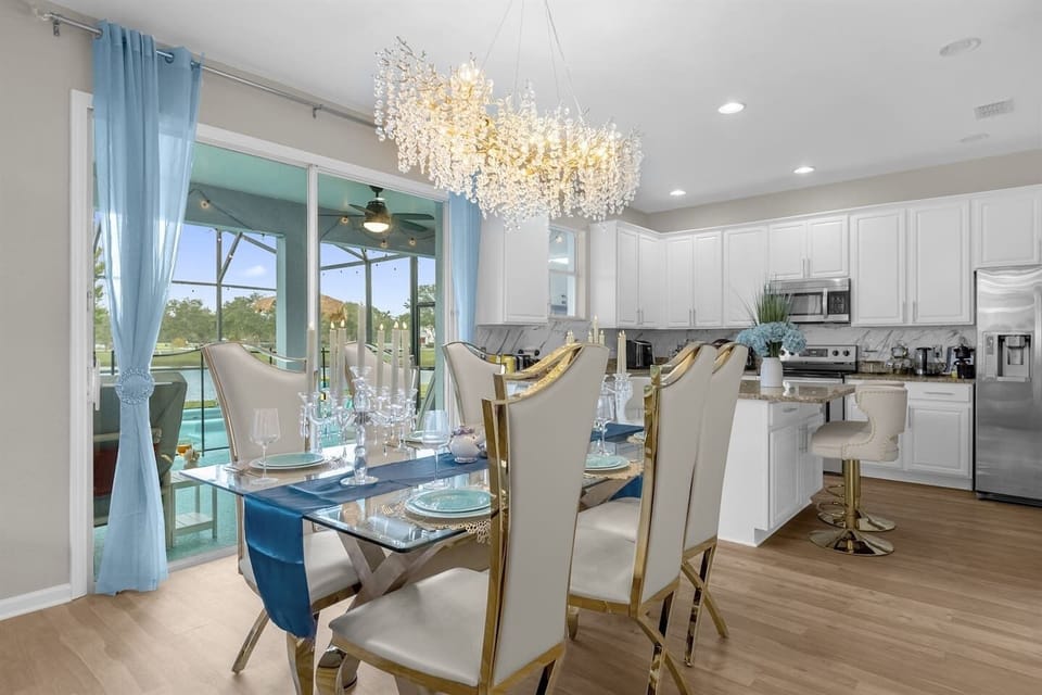 Dine in style beneath a sparkling chandelier — a fully stocked kitchen and elegant dining setup with views of the private pool.