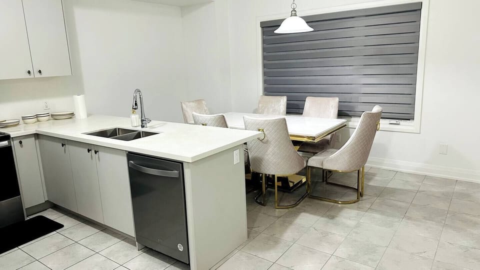 Modern dining area with a marble table, gold accents, and quilted beige chairs.