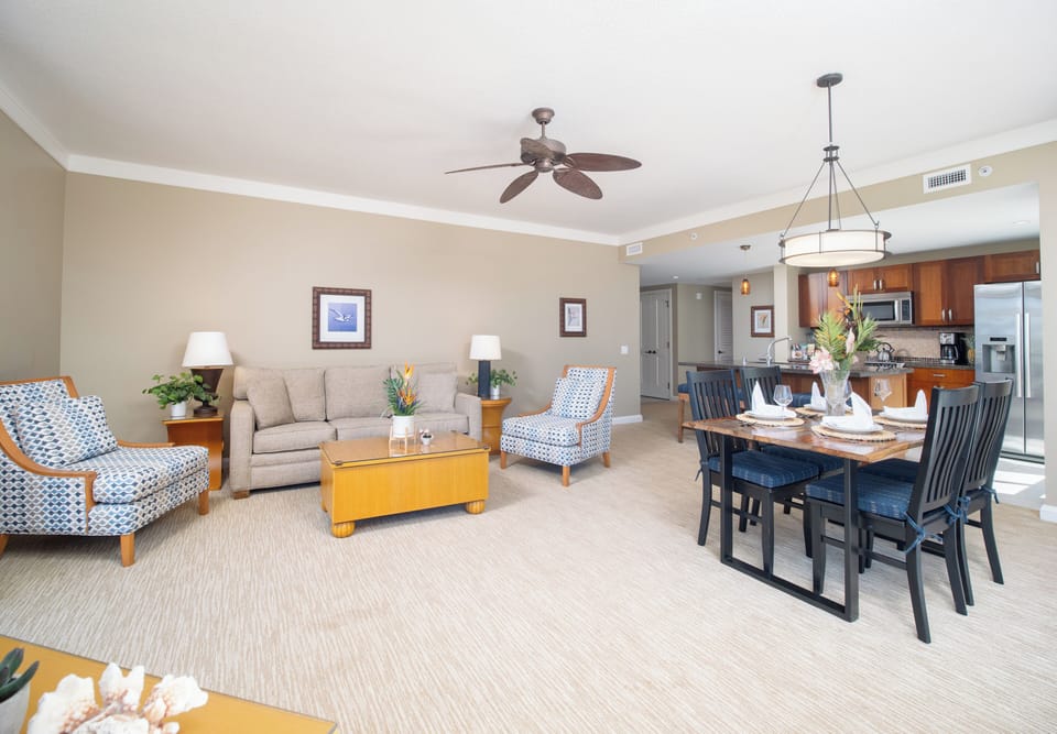 Bright and airy living room with modern furnishings, ideal for family gatherings and dining. Includes a ceiling fan for comfort.