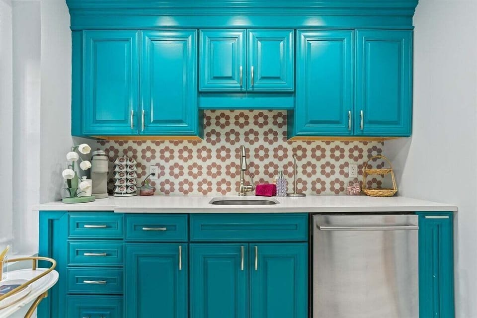 With turquoise cabinets, floral tile, and a countertop coffee station, this kitchen is a whole mood.