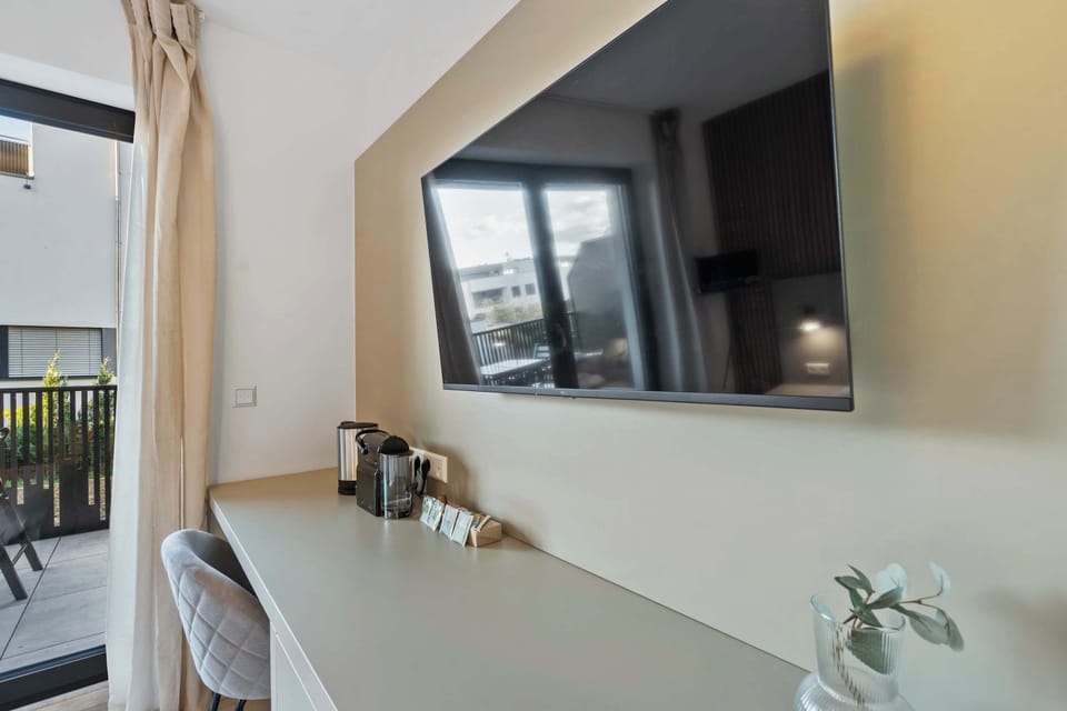 Functional Workspace and Entertainment Area – Wall-mounted TV, small desk, and a cozy chair create a perfect blend of comfort and productivity.