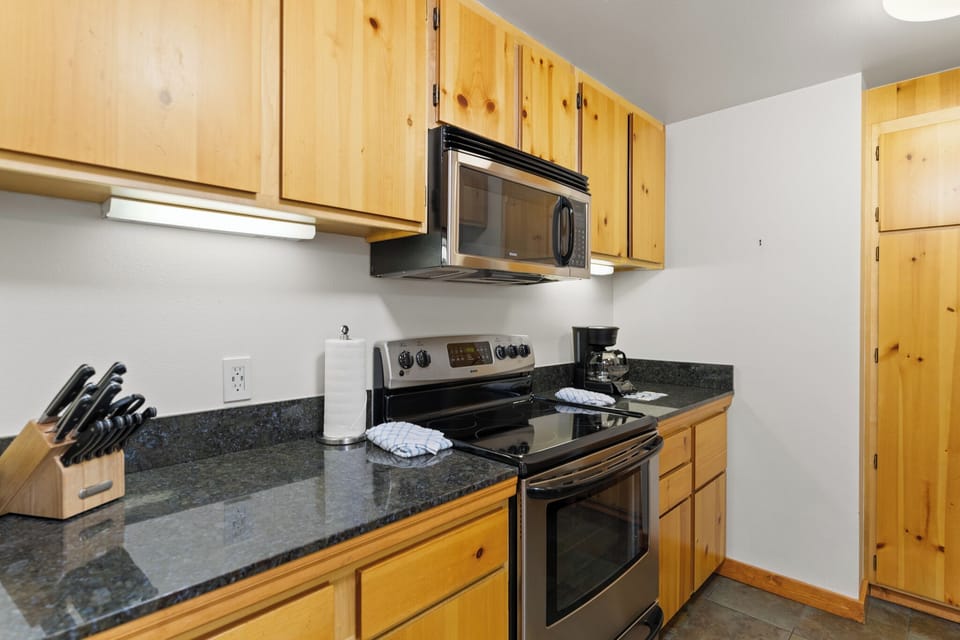 Full kitchen featuring stainless steel appliances and black granite countertops.