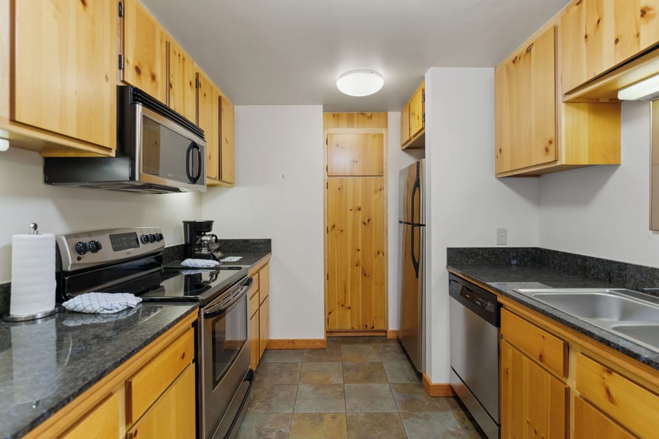 Full kitchen featuring stainless steel appliances and black granite countertops.