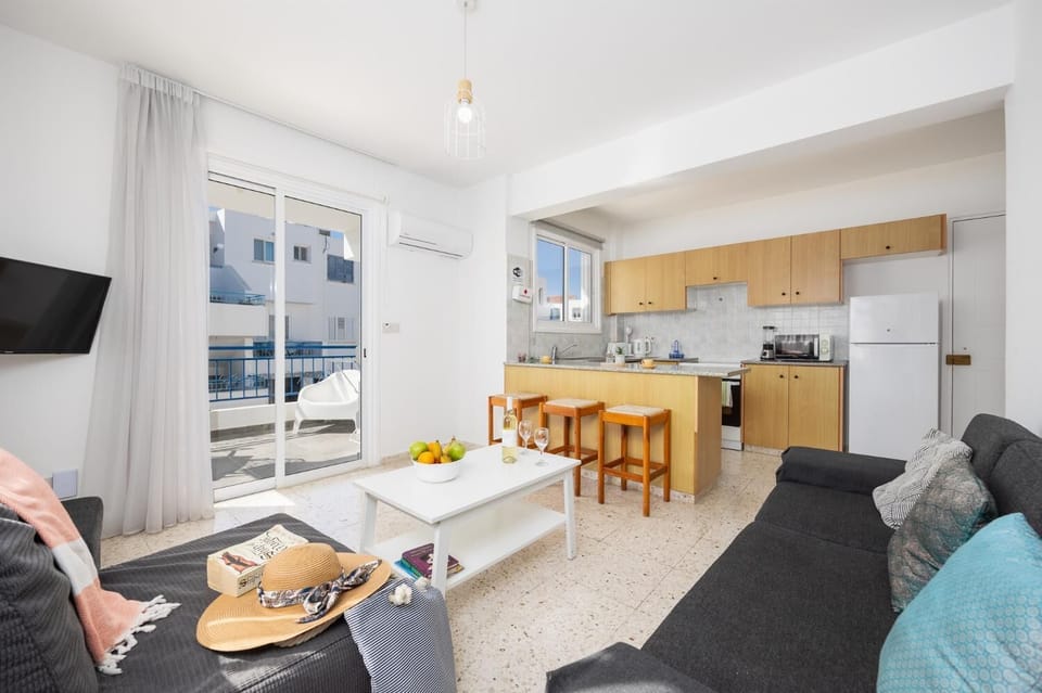 Open-plan living room with sofa, kitchen, A/C, WiFi internet, and satellite TV