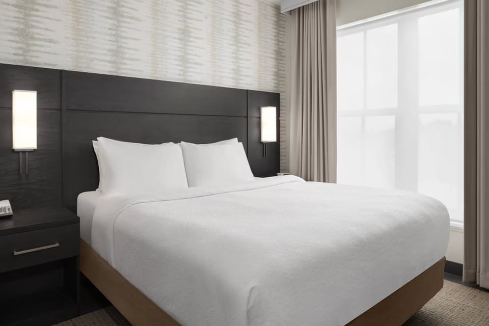 Unwind into a cloud-soft king bed beside bright windows.