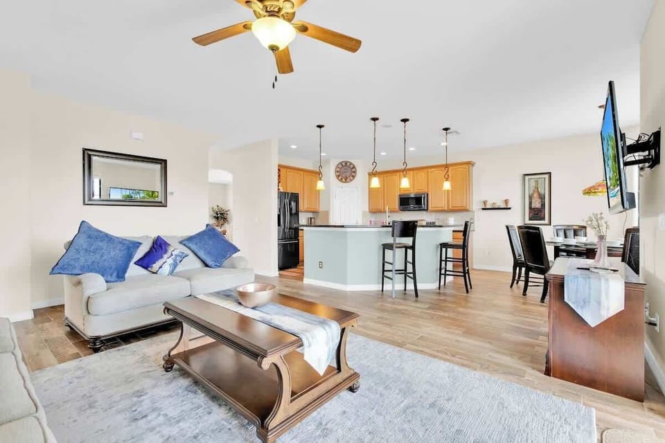 On the main floor, you'll find a open-concept kitchen and living room area, boasting a sleek TV, a kitchen bar, a dining table, and seamless access to the screened-in lanai.