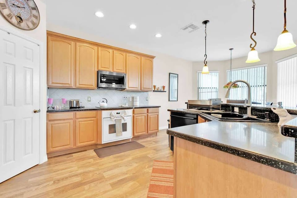 This open-plan kitchen is fully equipped with everything you need to whip up a delicious meal, including pots, pans, a cutting board, cooking utensils, and trusty appliances like a toaster and blender.