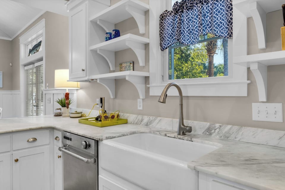 Your chef-inspired kitchen features marble countertops, farmhouse sink, and charming coastal details for memorable meal preparation.