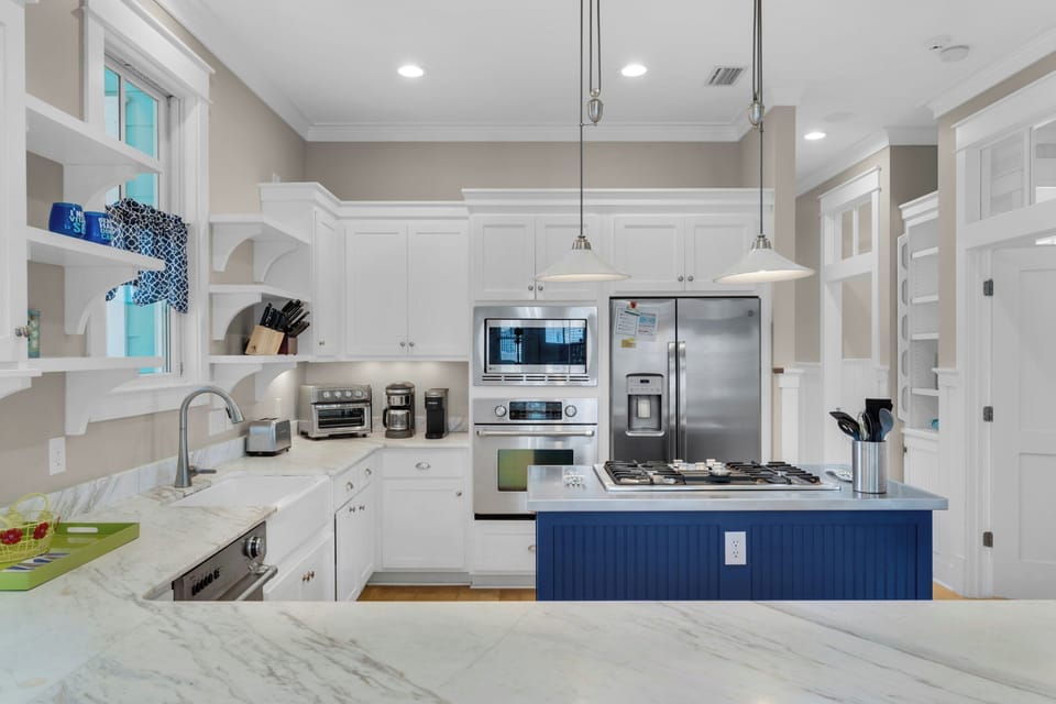 Your gourmet kitchen features marble countertops, stainless steel appliances, and a charming blue island perfect for preparing memorable meals together.