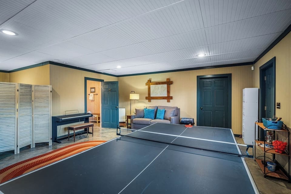 Bedroom 3/Game Room featuring a ping pong table, smart TV, two twin beds, sleeper sofa, full bathroom (tub/shower), and a mini fridge.