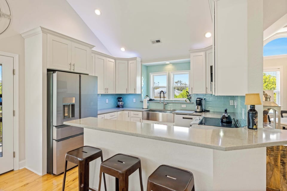 Bright White Kitchen w Stainless Steel Refrigerator, Microwave, Oven Range, Dishwasher, Sink, Cooking Utensils and Quartz Counters with Breakfast Bar