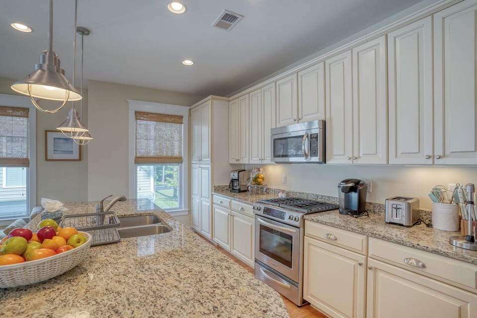 30220 Seaglass Way - Modern Chef’s Kitchen - : This upscale kitchen features crisp white cabinetry, high-end stainless steel appliances, and sleek granite countertops. The functional layout includes a breakfast bar with seating, perfect for casual morning meals.