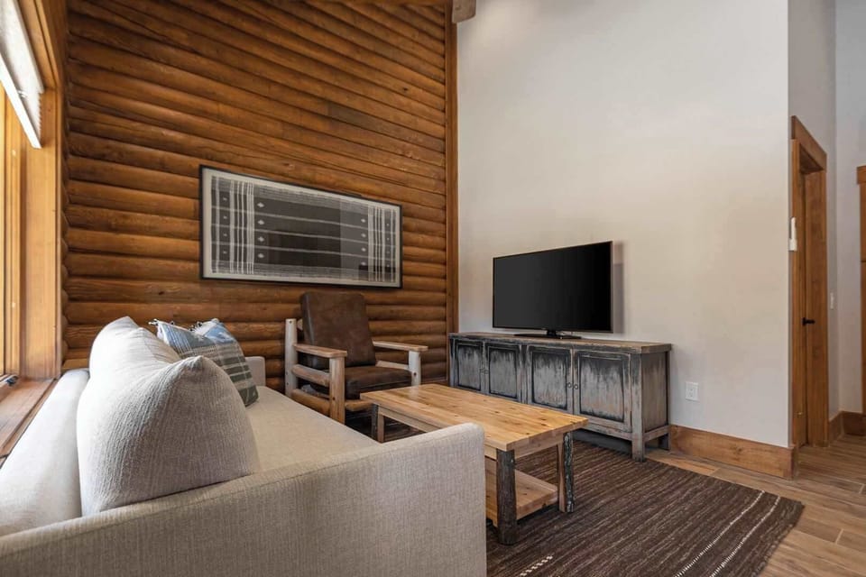 The Queen Room's cozy living space features handcrafted log furniture, plush seating, and warm, inviting textures for a perfect retreat.