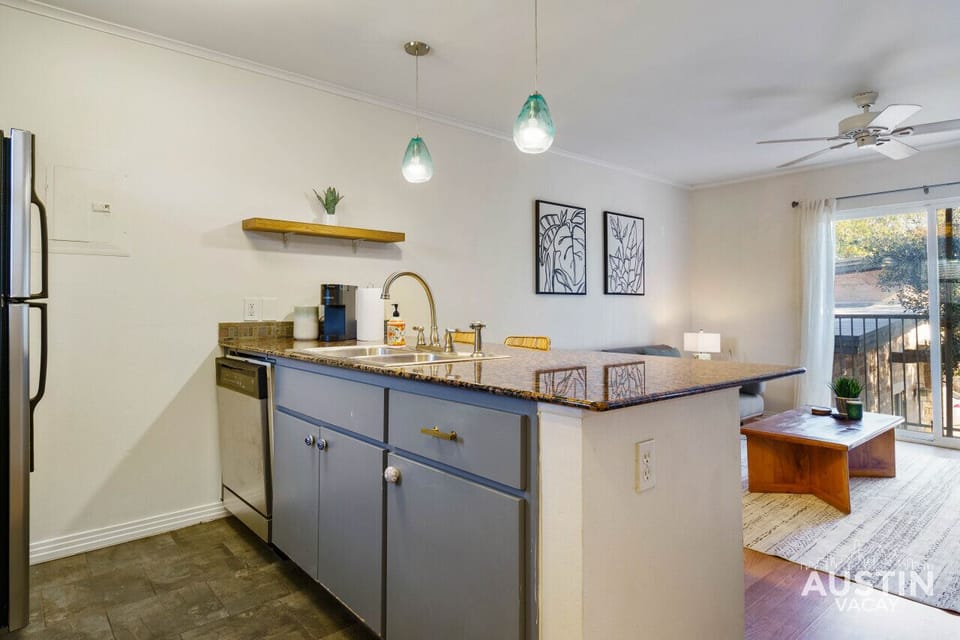 A kitchen featuring granite countertops, a built-in dishwasher, and unique pendant lighting