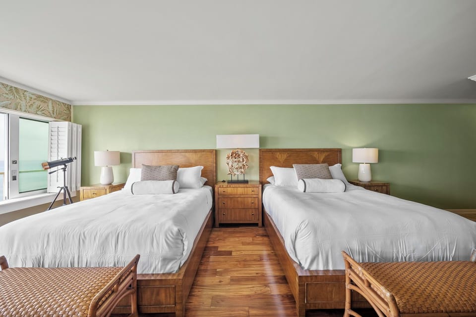 Cozy queen beds with hardwood floors, soft lighting, and inviting decor—perfect for a restful night by the ocean.