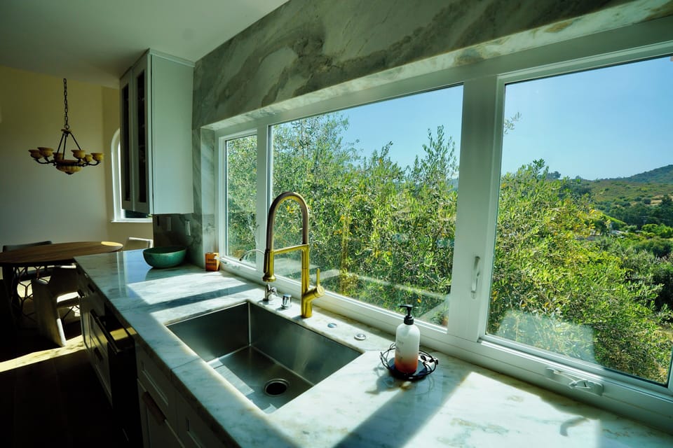 Kitchen overlooks pool area, trees, and mountains