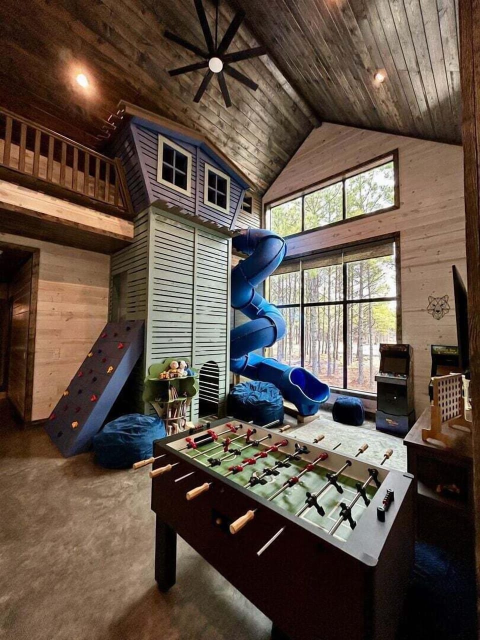 Game area which includes rock climbing wall, treehouse slide, arcade games & foosball table