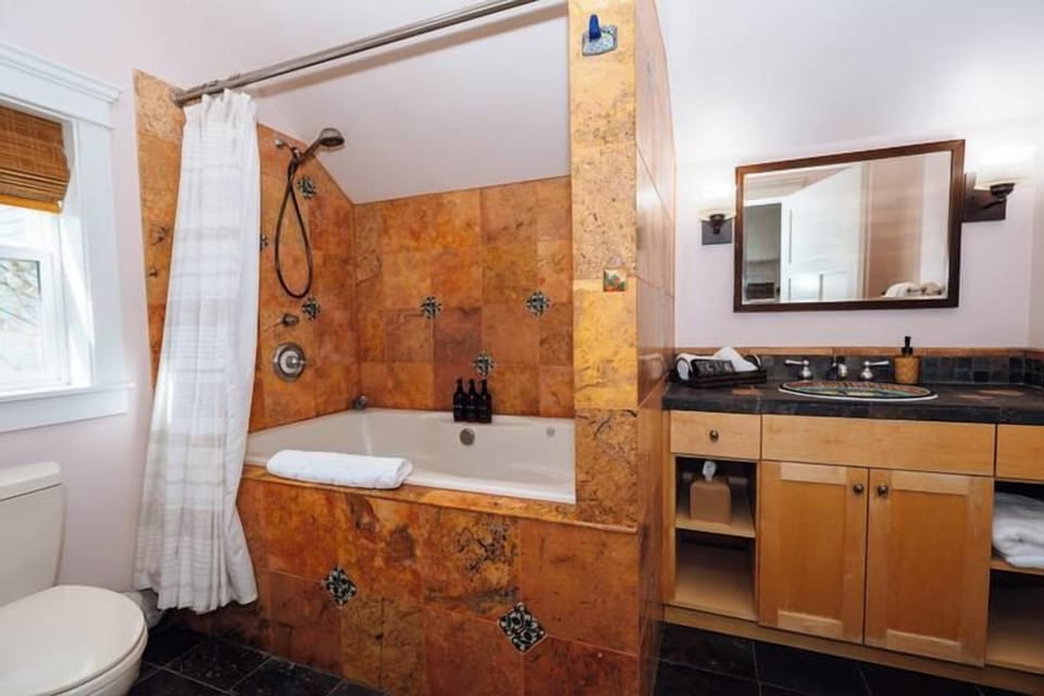 Swank 2: Elegant tiled bathroom complete with a deep soaking tub, overhead shower, and modern vanity.