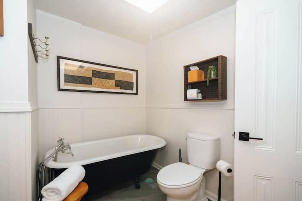 Swank 8: Elegant bathroom corner featuring a vintage clawfoot tub, toilet, and decorative wall storage.