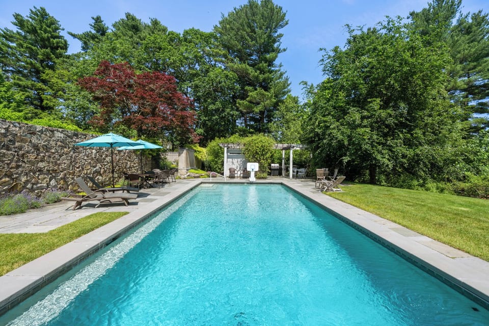 Dive into luxury in this private, resort-style pool surrounded by lush trees and elegant stonework—perfect for family fun or peaceful relaxation. Lounge in the sun or enjoy shaded seating under umbrellas in this beautifully landscaped oasis.
