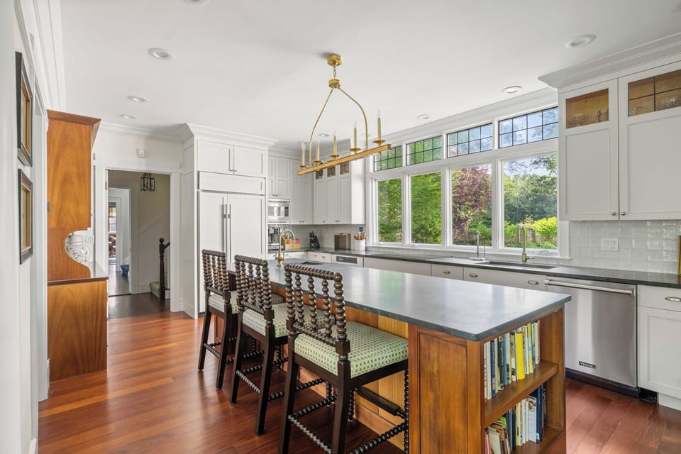 This bright, gourmet kitchen features luxury finishes, a spacious island with seating, and stunning garden views — perfect for family breakfasts or cooking together. Thoughtful touches like built-in bookshelves and top-tier appliances elevate every stay.
