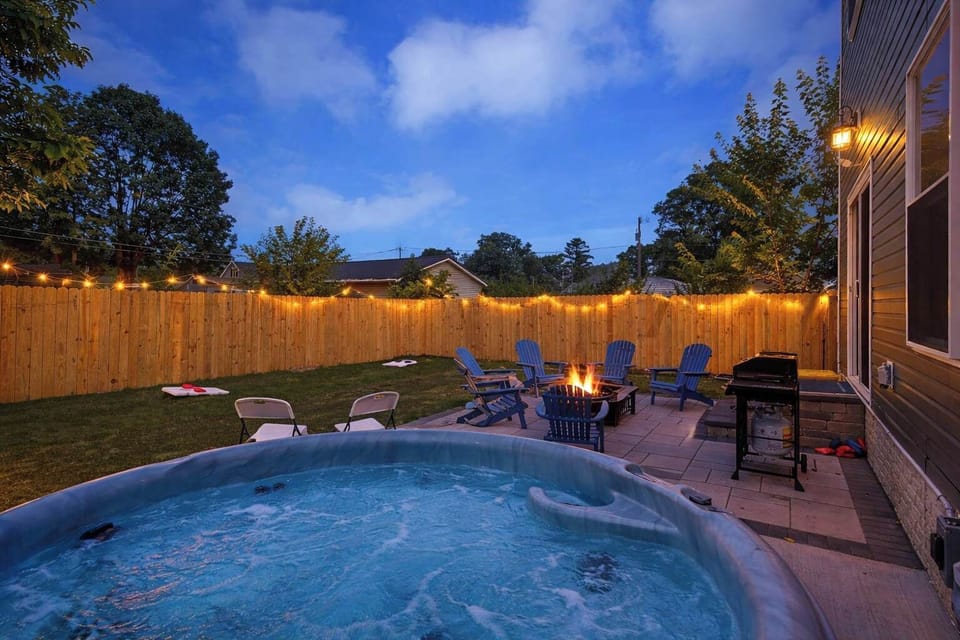 Private backyard oasis at night — relax in the 6-person hot tub, gather around the fire pit, grill dinner, and unwind under the string lights.
