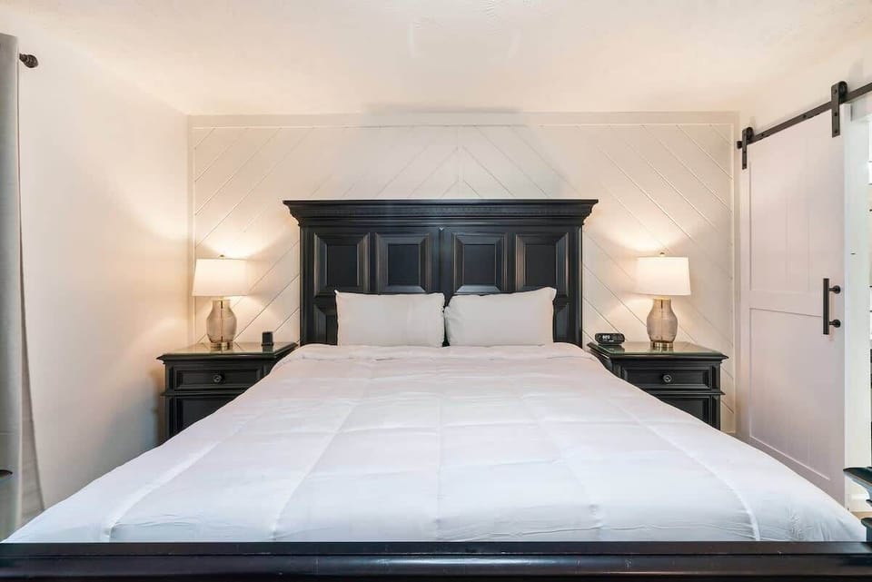King-size bed with black wooden headboard and matching nightstands in a modern bedroom.