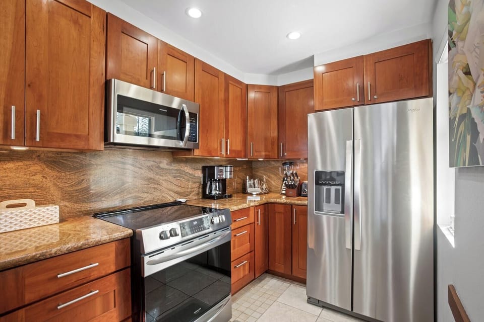 This glossy wood-toned kitchen feels like a warm hug—where coffee brews strong, and breakfasts come with a tropical twist  