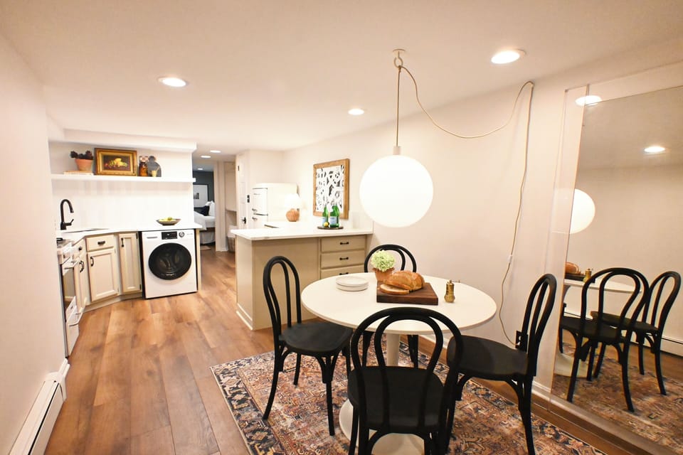 Chic dining area with table for 4, floor-length mirror & stylish lighting. 