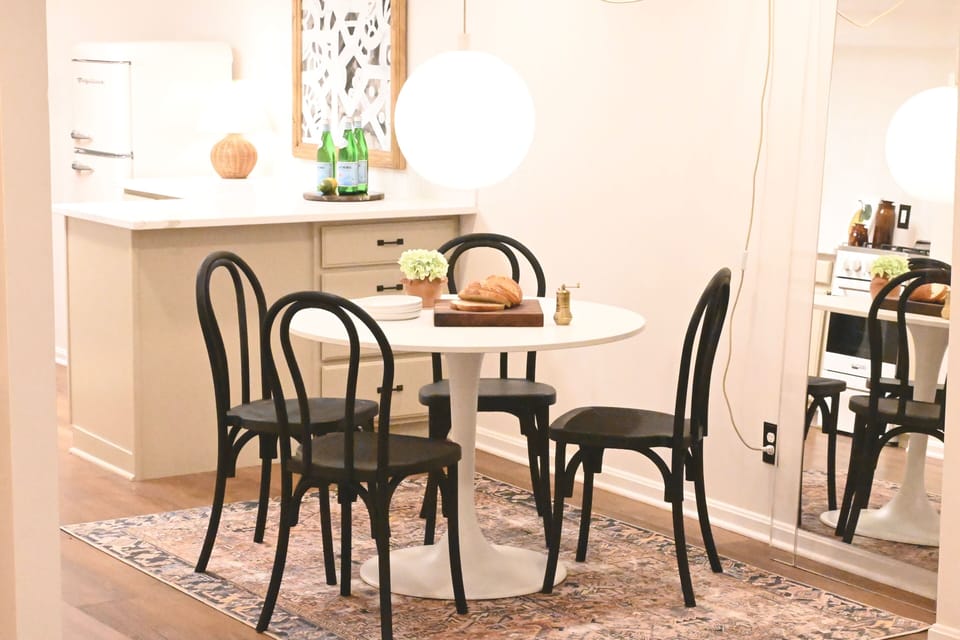 Chic dining area with table for 4, floor-length mirror & stylish lighting. 
