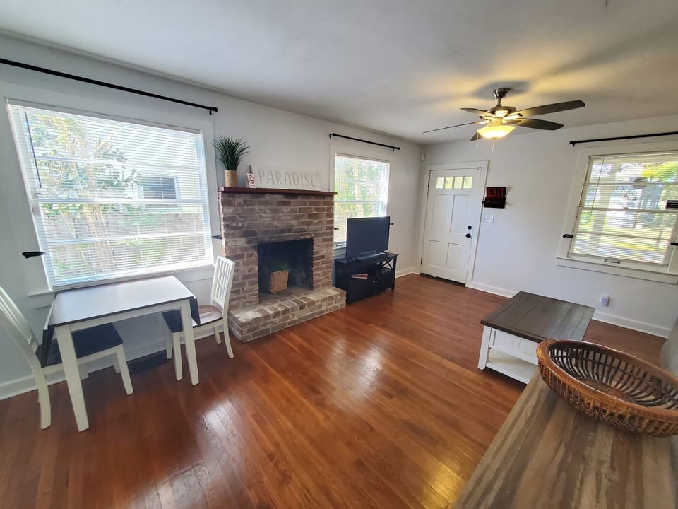 Bright living room with rustic brick fireplace and hardwood floors.