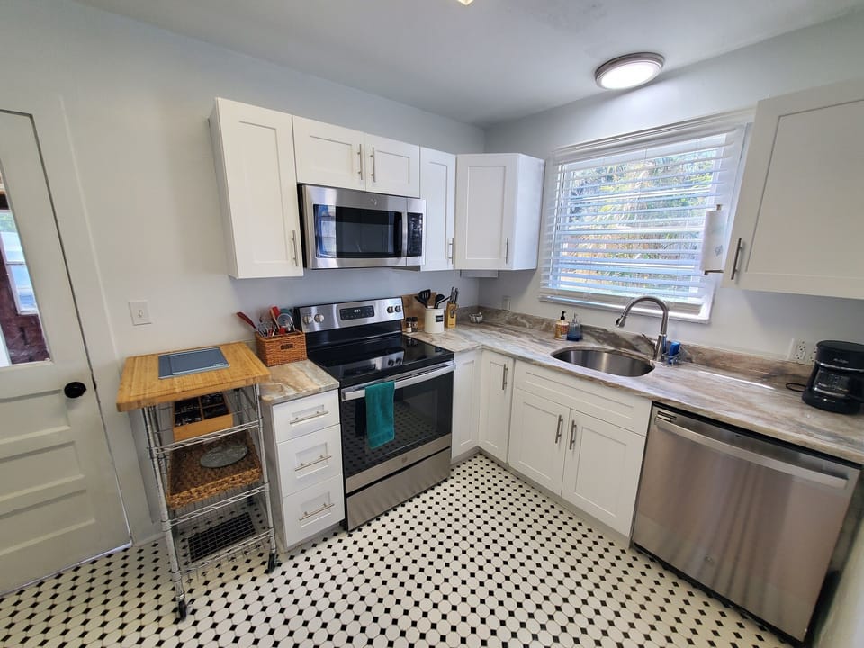 Modern kitchen with stainless steel appliances and chic black-and-white flooring.