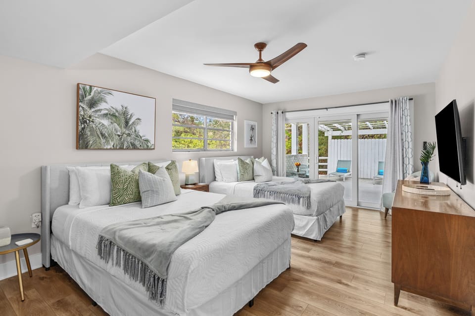 Bedroom 5 features two queen beds, a TV, and access to the patio.