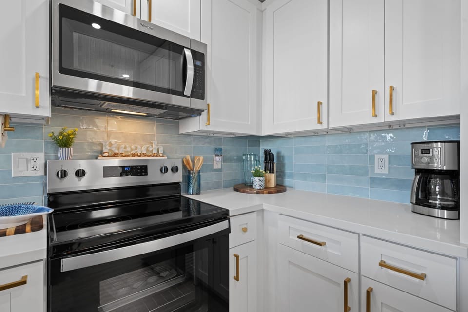 Stylish quartz countertops, personalized tile backsplash, and stunning white cabinets