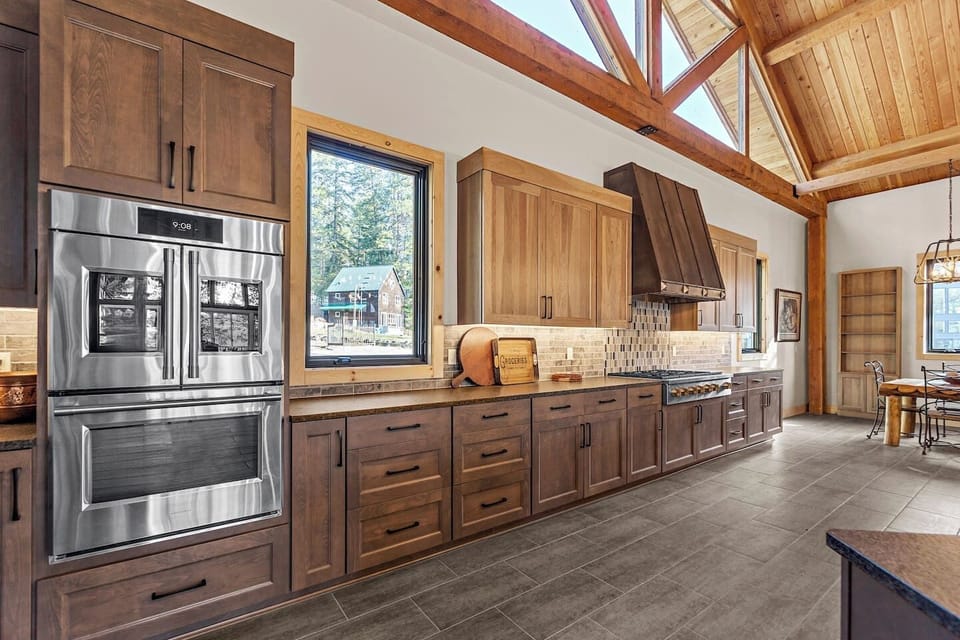A clockwise tour around the kitchen island starts with a large stainless steel refrigerator and freezer with an ice maker, followed by two wall ovens and a six-burner gas range, providing ample space for culinary creations.