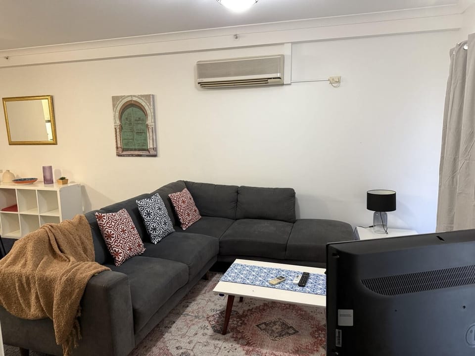 Experience comfort and convenience! This living room features a comfortable sofa, a practical table, soft carpet, and a TV for your entertainment.