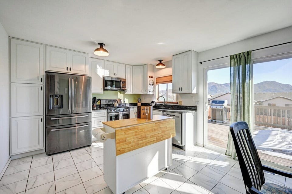 Dine in kitchen features sliding glass doors which open to the deck that includes a gas grill and BBQ utensils. 